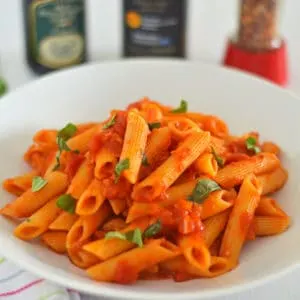Penne all'Arrabbiata in a bowl with torn herbs