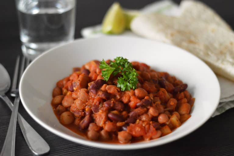mixed bean chilli in a bowl with tortilla and lime on the side