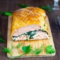 Salmon en croute cut in half on a chopping board.