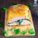 Salmon en croute cut in half on a chopping board.