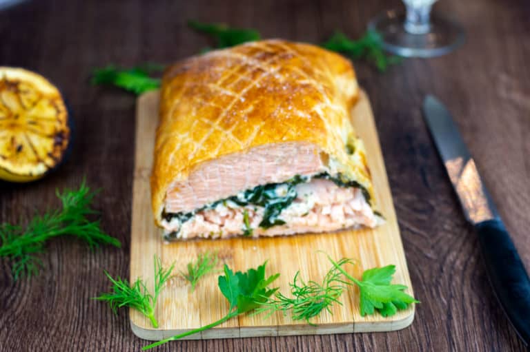 Salmon en croute cut in half on a chopping board.