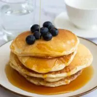 American Pancakes with blueberries with maple syrup being drizzled on top