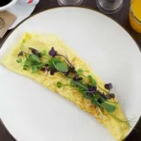 Omelette on a plate served with toast, coffee & orange juice