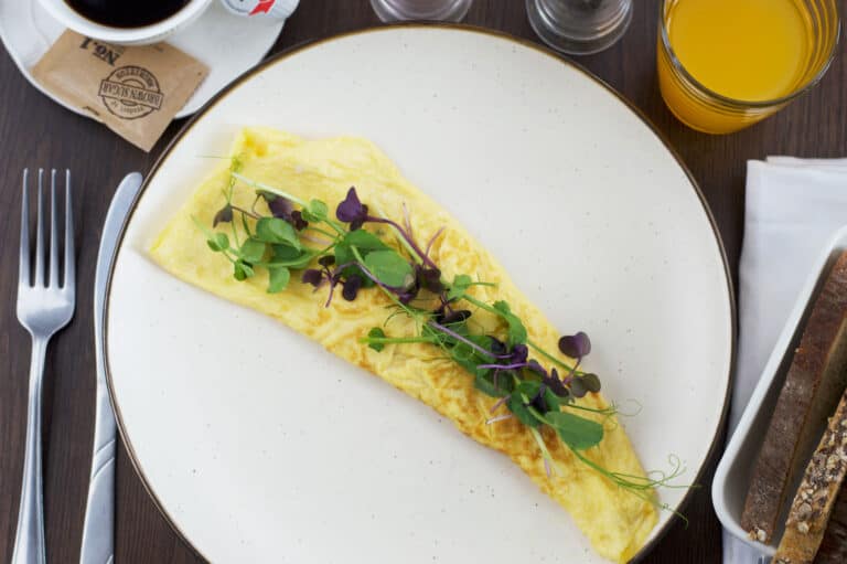 Omelette on a plate served with toast, coffee & orange juice