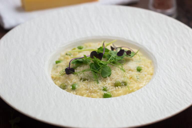 Truffle oil orzo pasta topped with panko breadcrumbs and micro herbs in a white bowl.