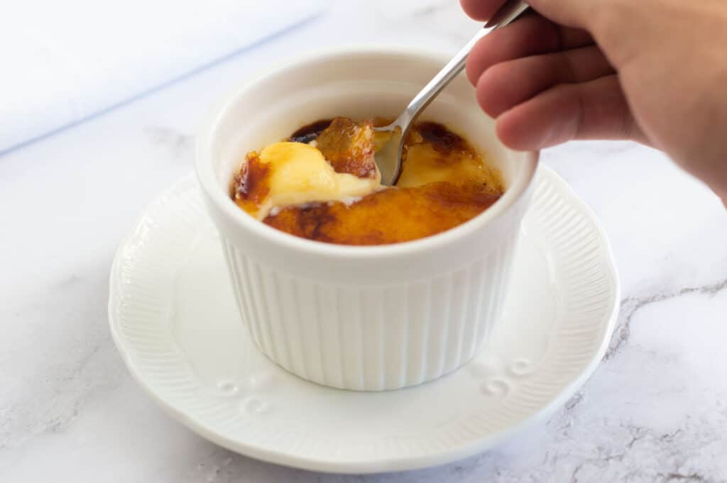 Breaking the caramel with a teaspoon on the creme brûlée