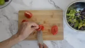 Me cutting the stalk out of the middle of the tomato on a wooden chopping board