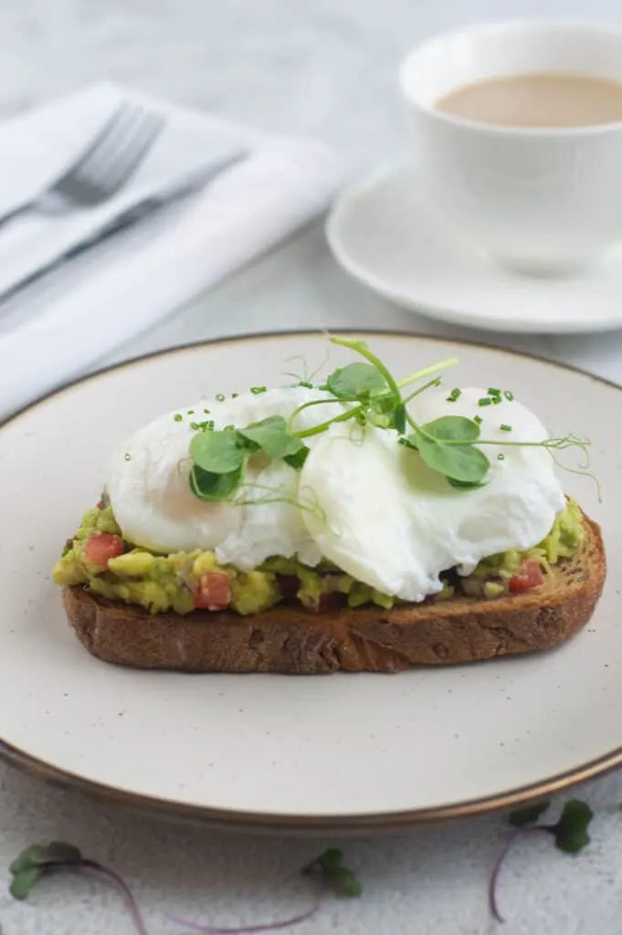 Poached eggs with smashed avocado on toast with coffee