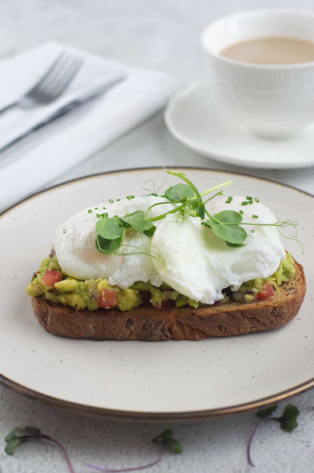 Poached eggs with smashed avocado on toast with coffee.