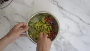 Mixing together avocado, tomato and onion in a mixing bowl