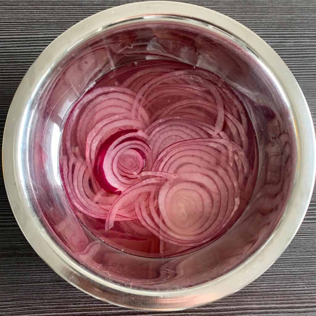 Pickled red onions, finely sliced in a mixing bowl