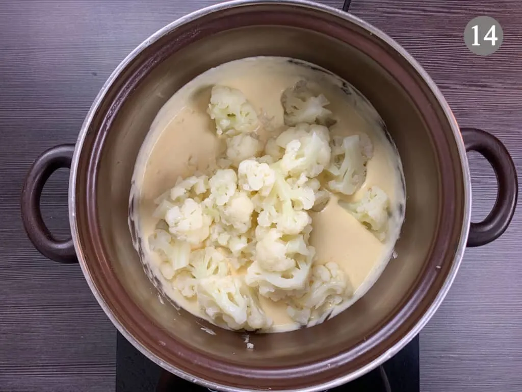 Cauliflower being added to a pot of cheese sauce