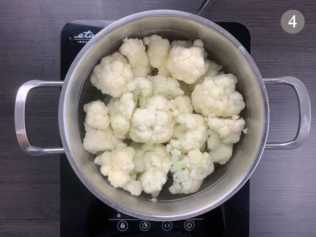 Cauliflower being boiled in a medium pot on a hob