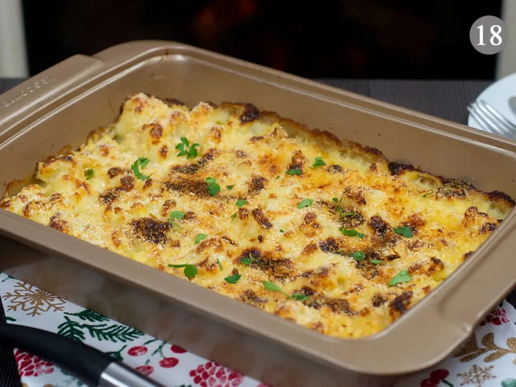 A baking tray with freshly baked cauliflower cheese on a table, with a fireplace in the background.