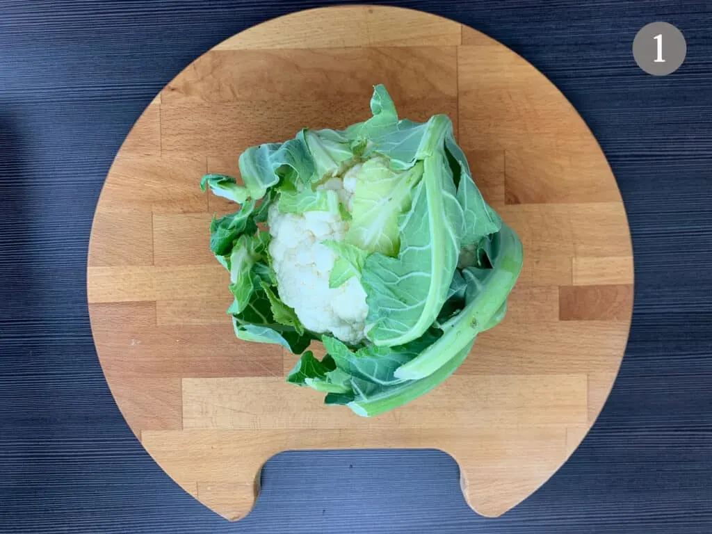 A non prepped cauliflower on a chopping board