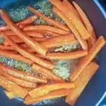 Carrots glazing in a pan with butter and brown sugar