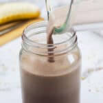 Weight Gainer Smoothie being poured into a mason jar with a sliced banana in the background