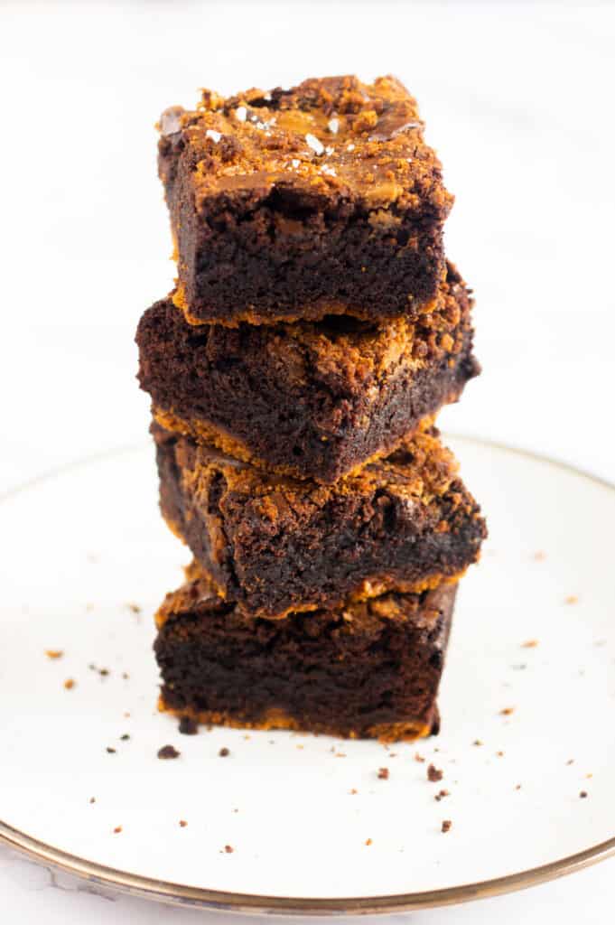 A stack of four gooey biscoff brownies with a sprinkle of flakey sea salt on top