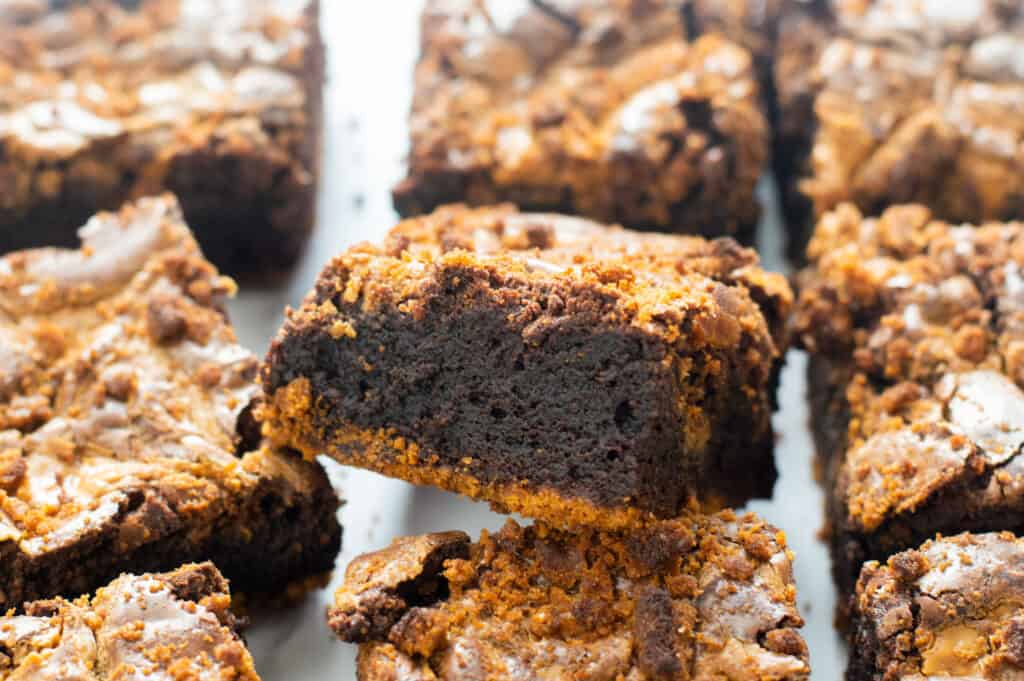 Nine Biscoff Brownies cut into portions with one showing a fudgy, gooey center