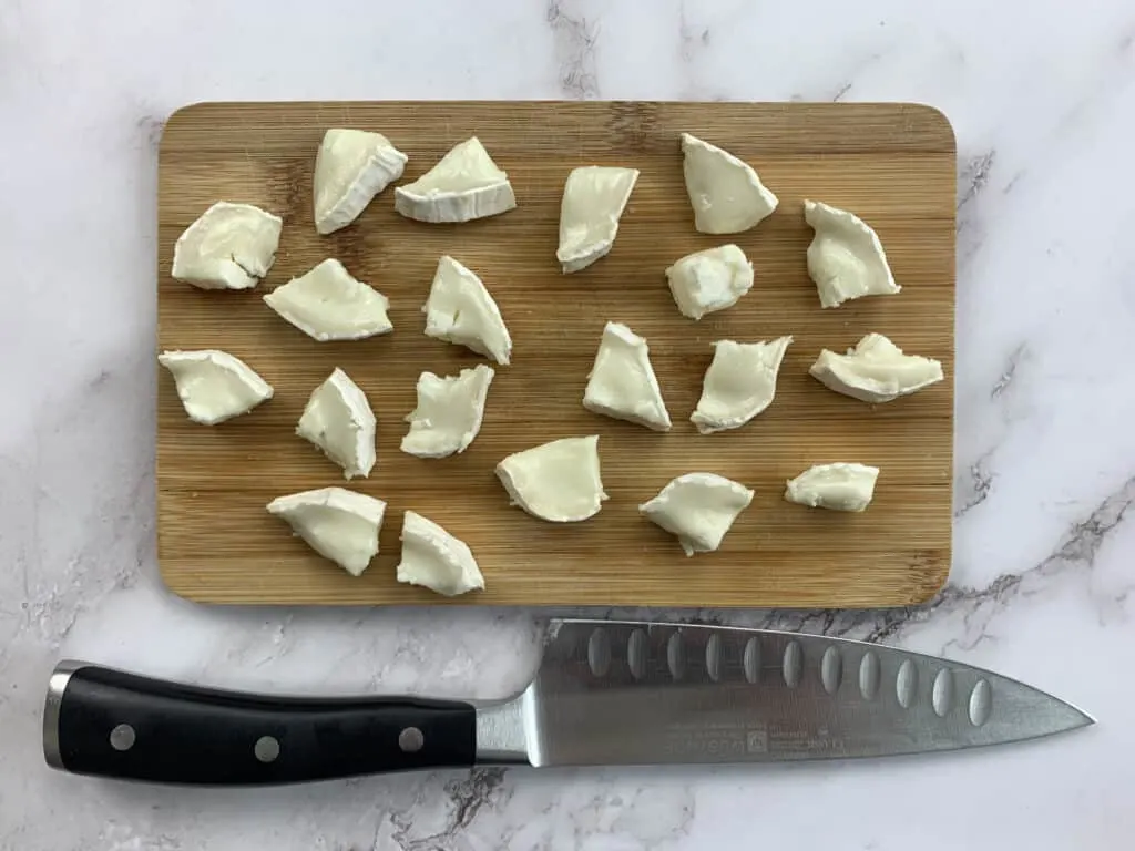 Goats cheese cut into pieces on a chopping board