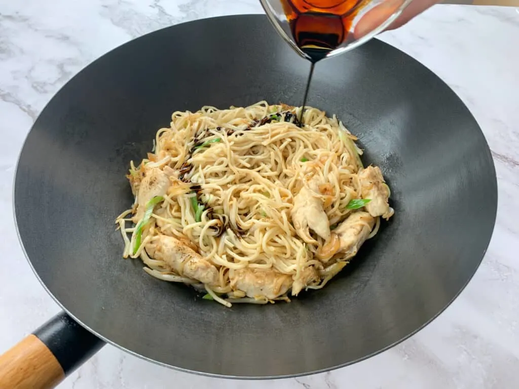 Drizzling dark soy sauce into the noodles