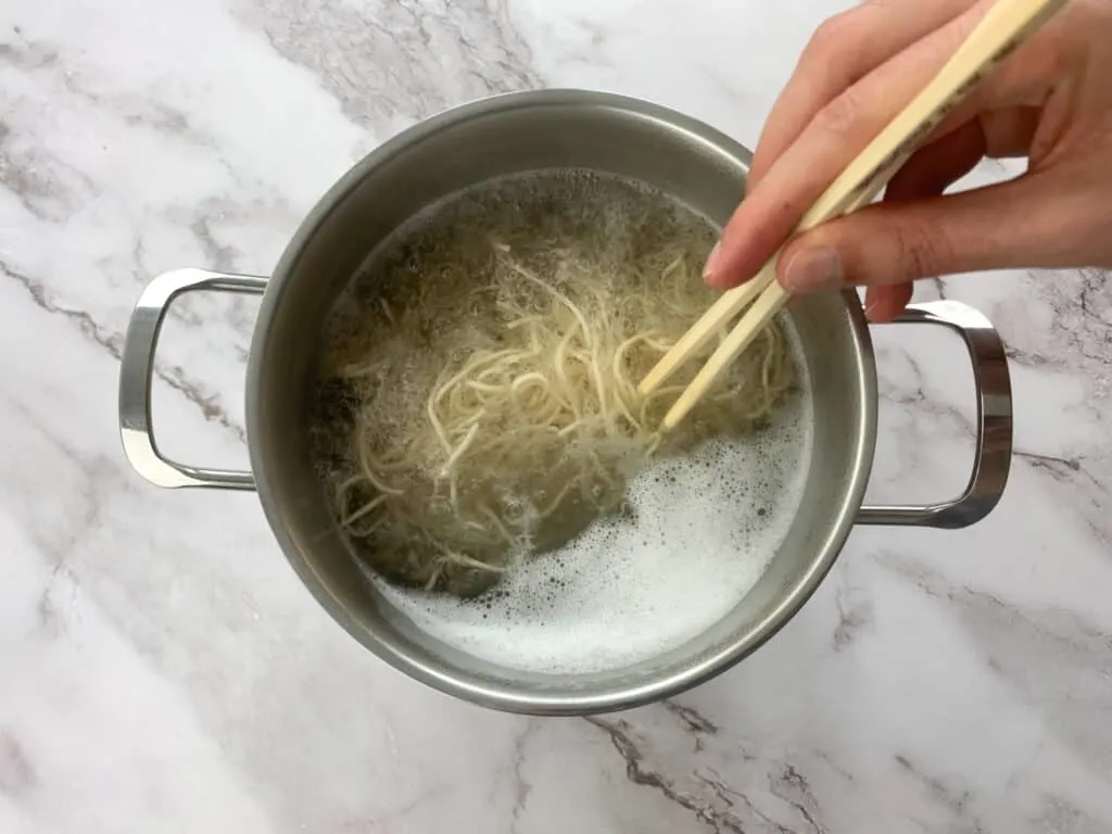 Mixing a large pot of cooking noodles