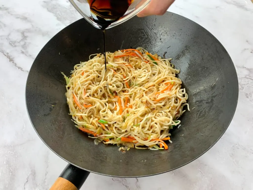 Adding soy sauce to the chow mein