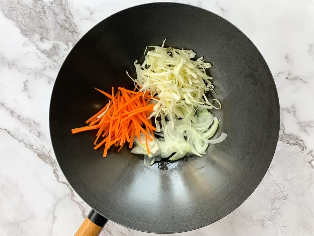 carrots, cabbage and onions in a large wok