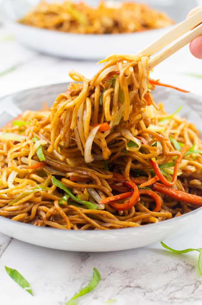 Chopsticks grabbing some noodles out of a bowl