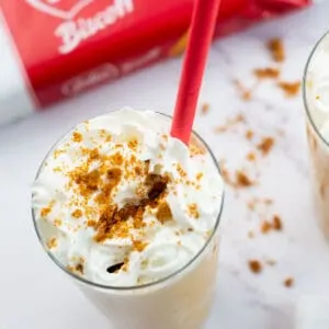 Biscoff milkshake in a tall glass and a red straw