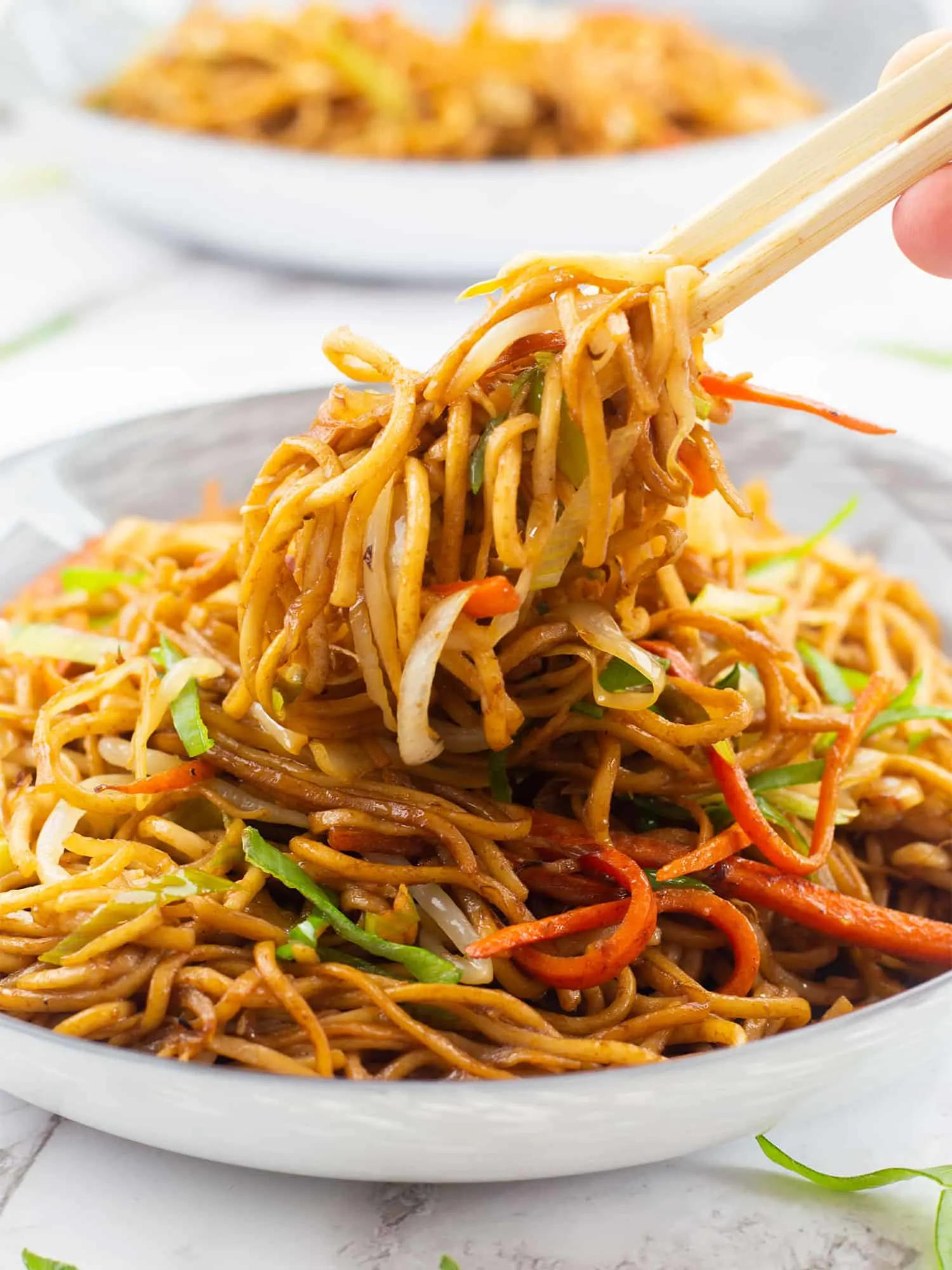Vegan Chow mein being picked up with chop sticks