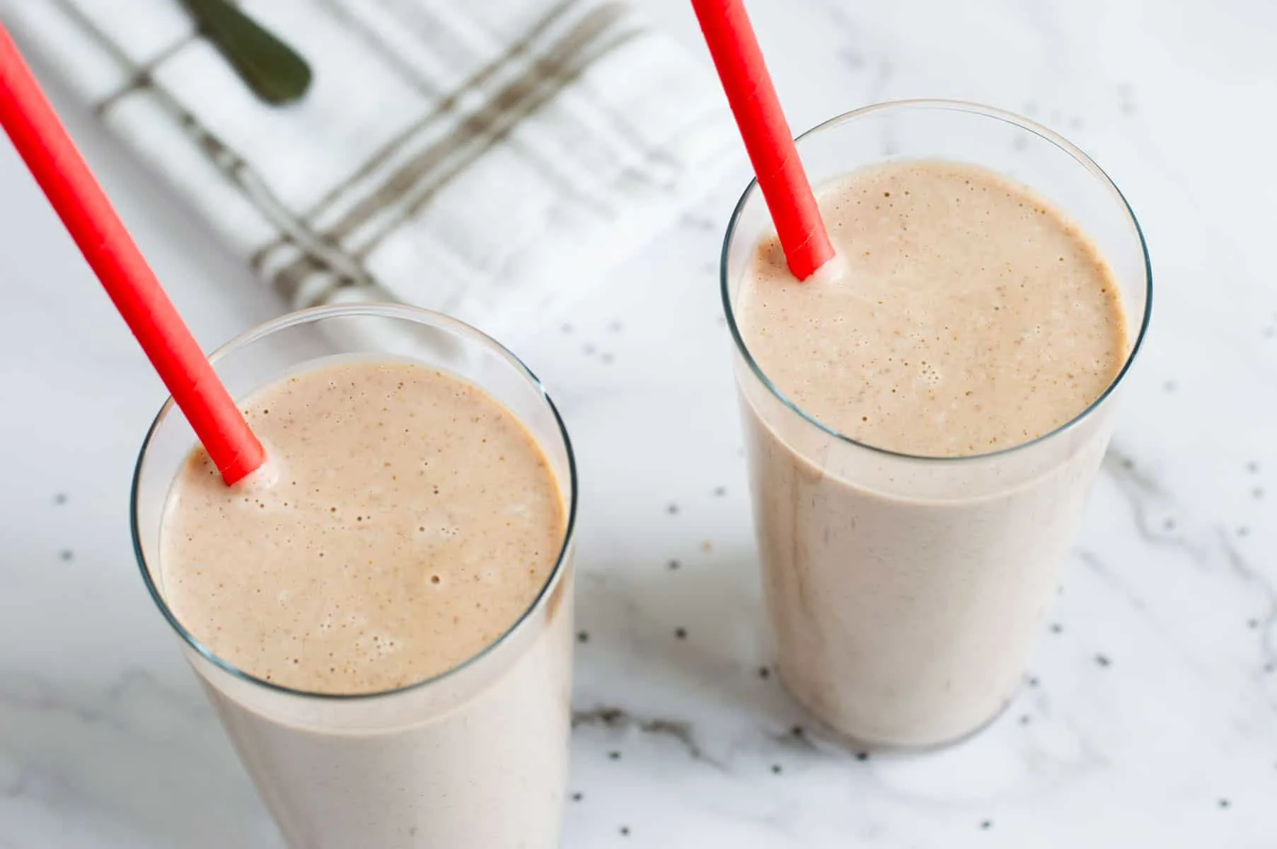 two vegan keto smoothies in a glass with a red straw