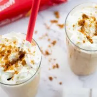 Two biscoff milkshakes with whipped cream and crushed biscuits