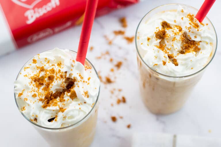 Two biscoff milkshakes with whipped cream and crushed biscuits