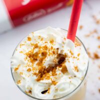 Biscoff milkshake in a tall glass and a red straw