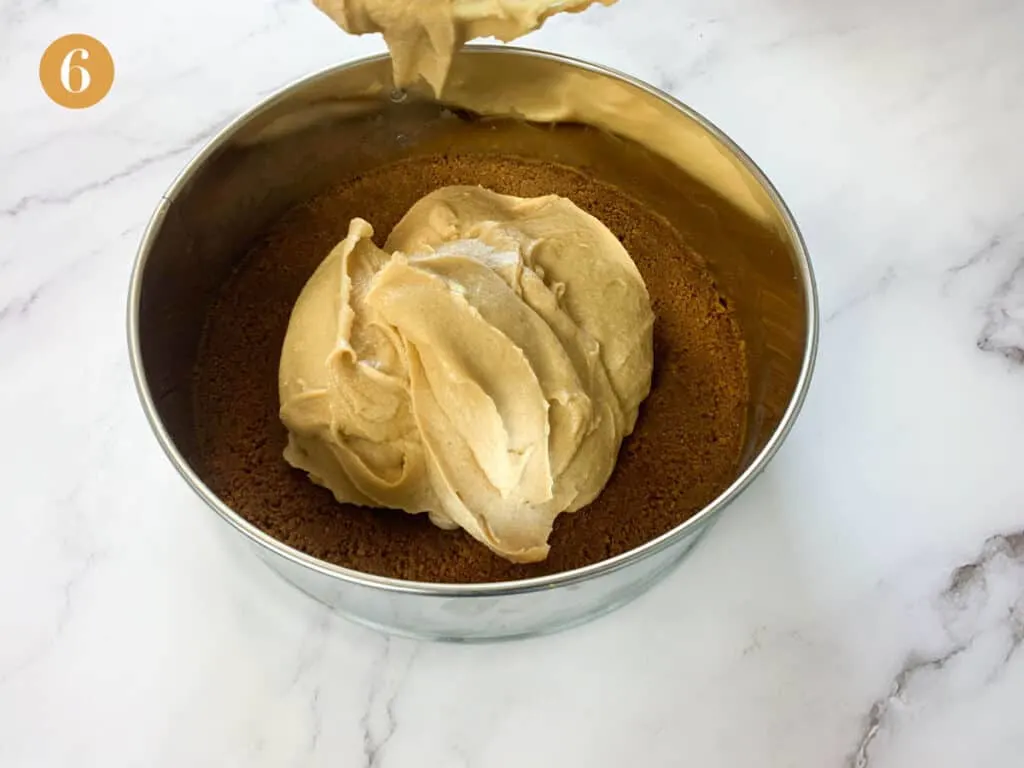 Pouring the biscoff filling into a cake tin with a biscuit crumb