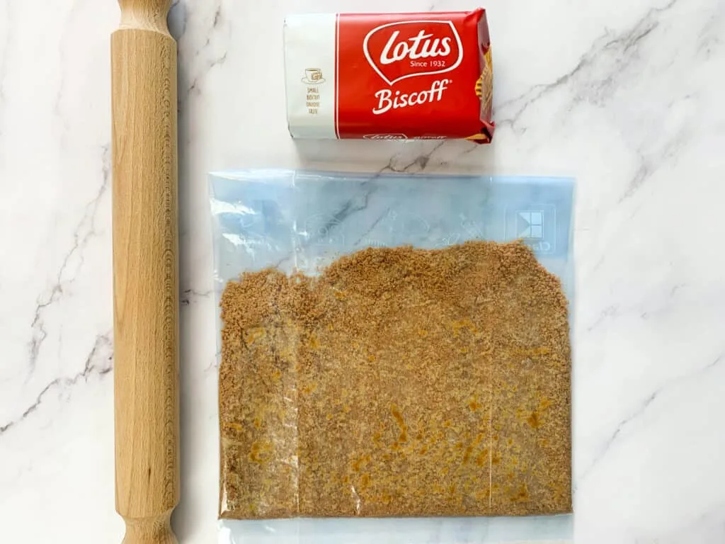 Biscoff biscuits finely crushed in a freezer bag with a rolling pin