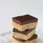 Three protein bars stacked on top of a marble counter top