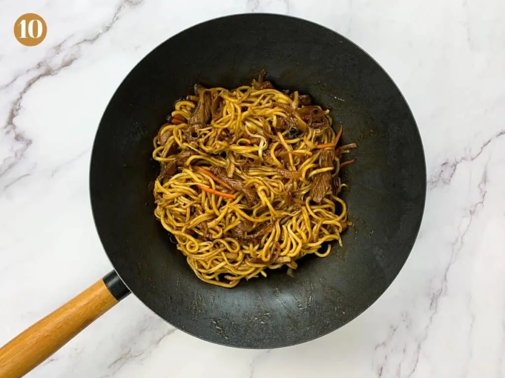 Noodles mixed into beef steak yaki soba in wok