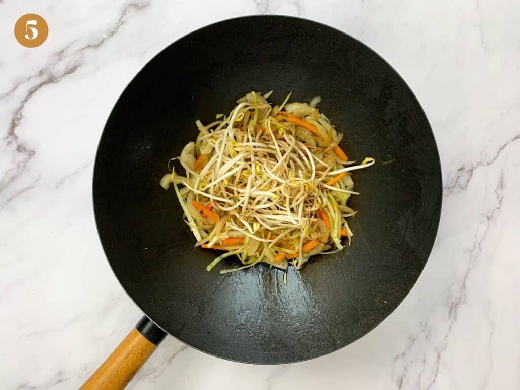 Bean sprouts on top of stir fried cabbage, carrots and onions