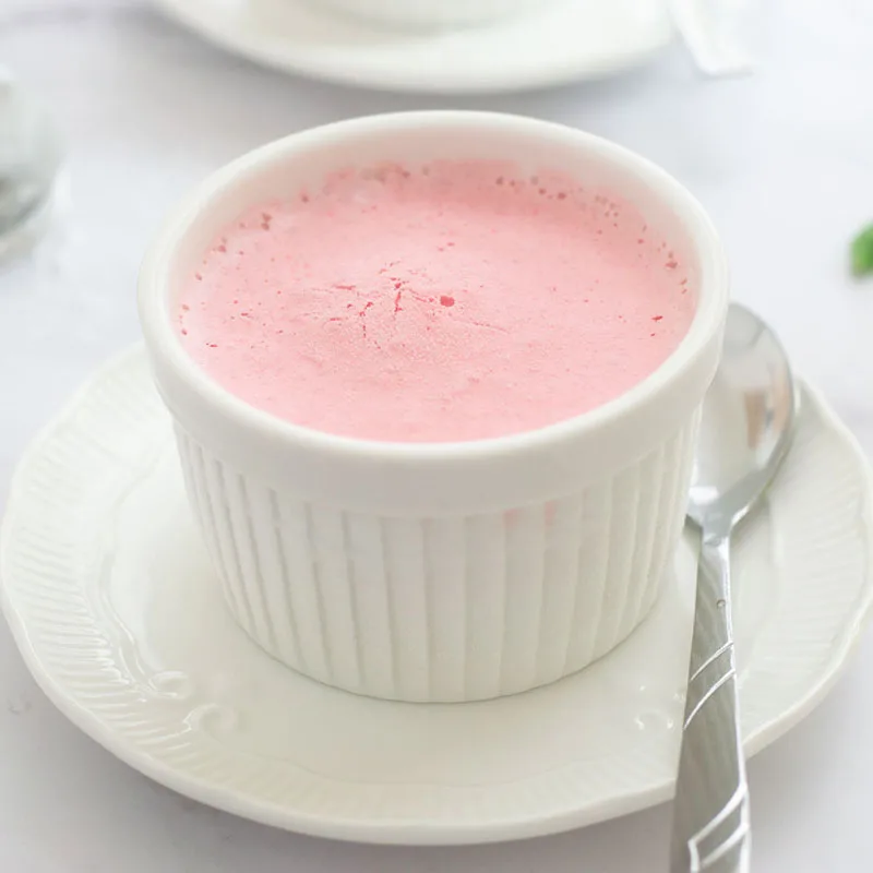 Frozen strawberry mouse in a white ramekin and on a fancy white serving dish