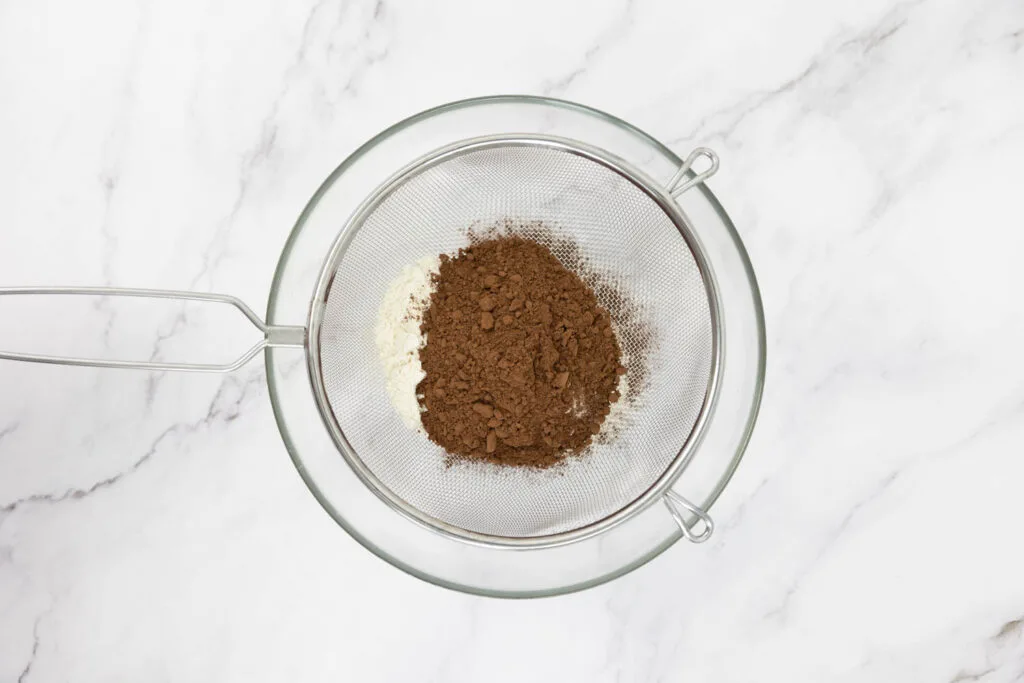 Flour and cocoa being sieved into a large bowl