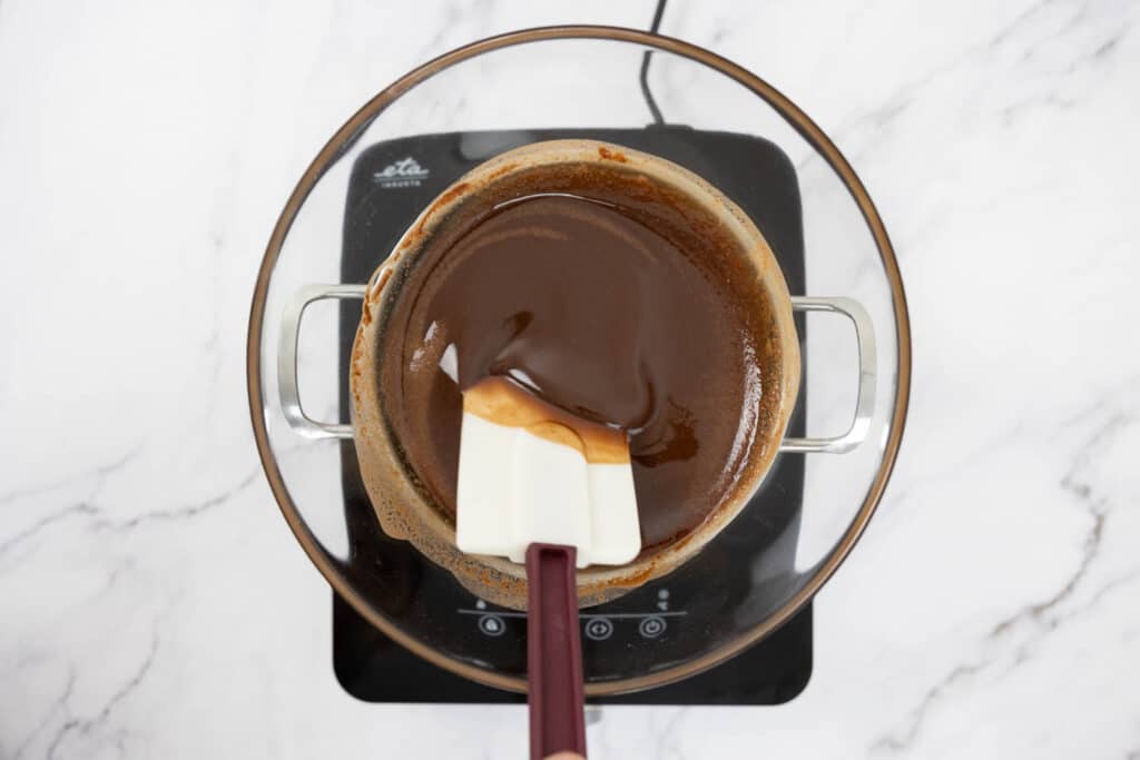 Melted butter and chocolate being mixed with a plastic spatula on top of a pot