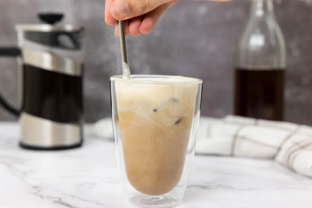 Mixing together the salted caramel cream cold brew with a reusable straw