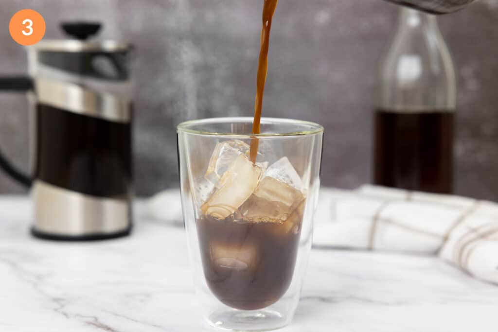 Pouring cold brew into a glass of ice