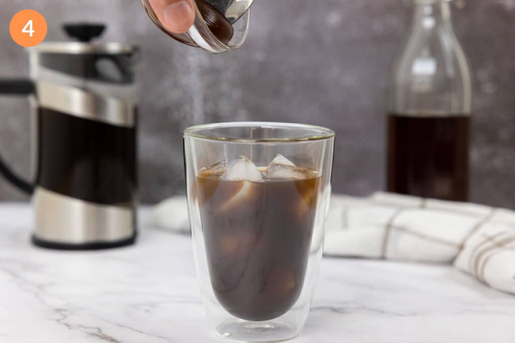 Pouring salted caramel sauce into a glass of cold brew and ice