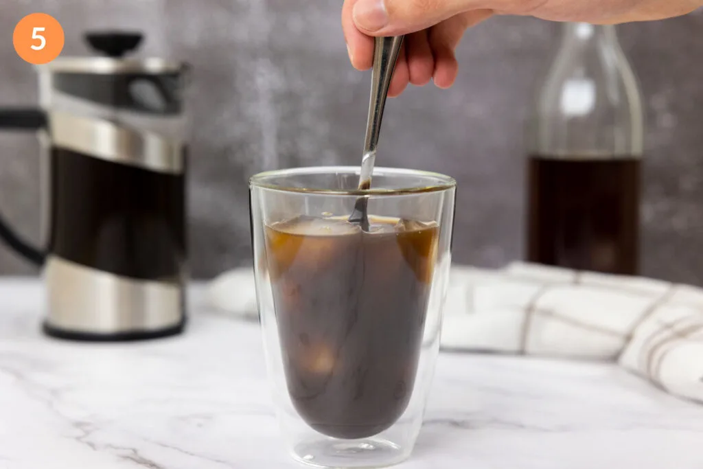 Mixing salted caramel into an iced cold brew with a spoon