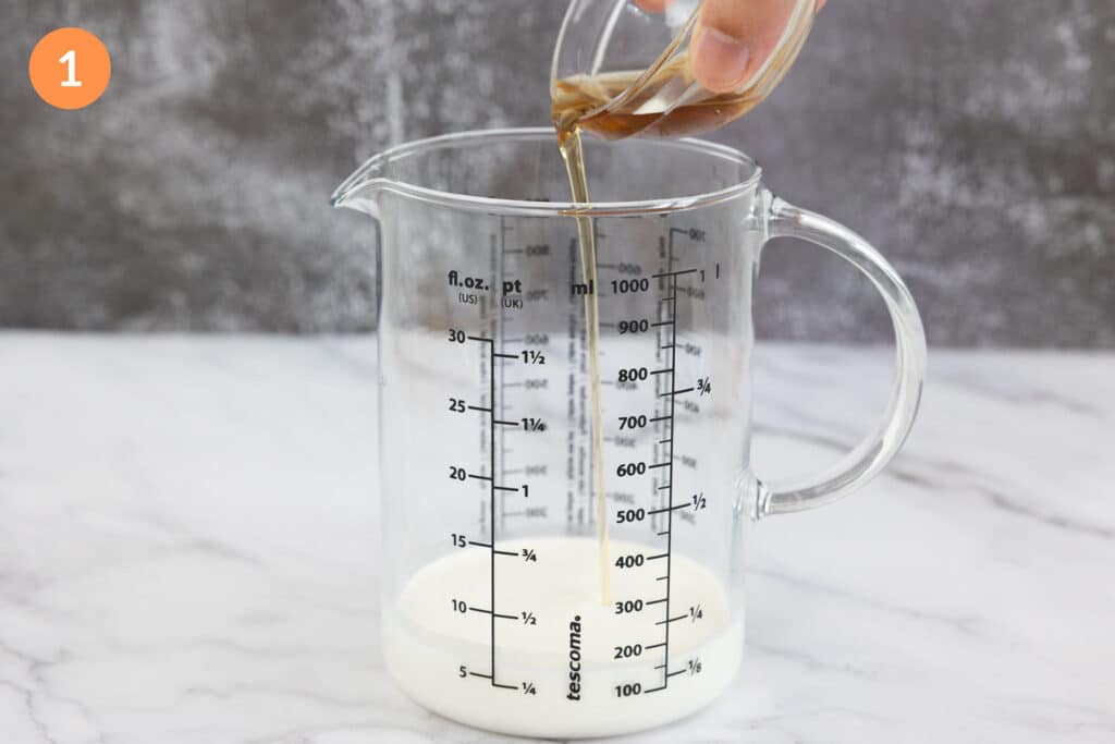 Pouring vanilla syrup into a jug of cream and milk