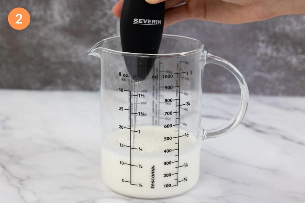 Mixing vanilla sweet cream cold foam with a electric foamer in a jug