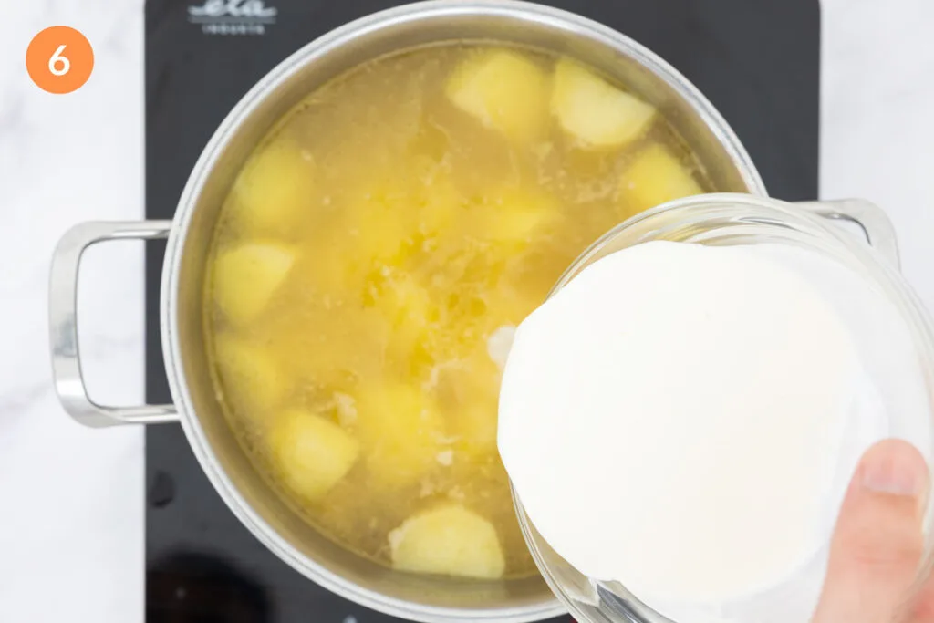 Pouring cream into chicken stock and potatoes